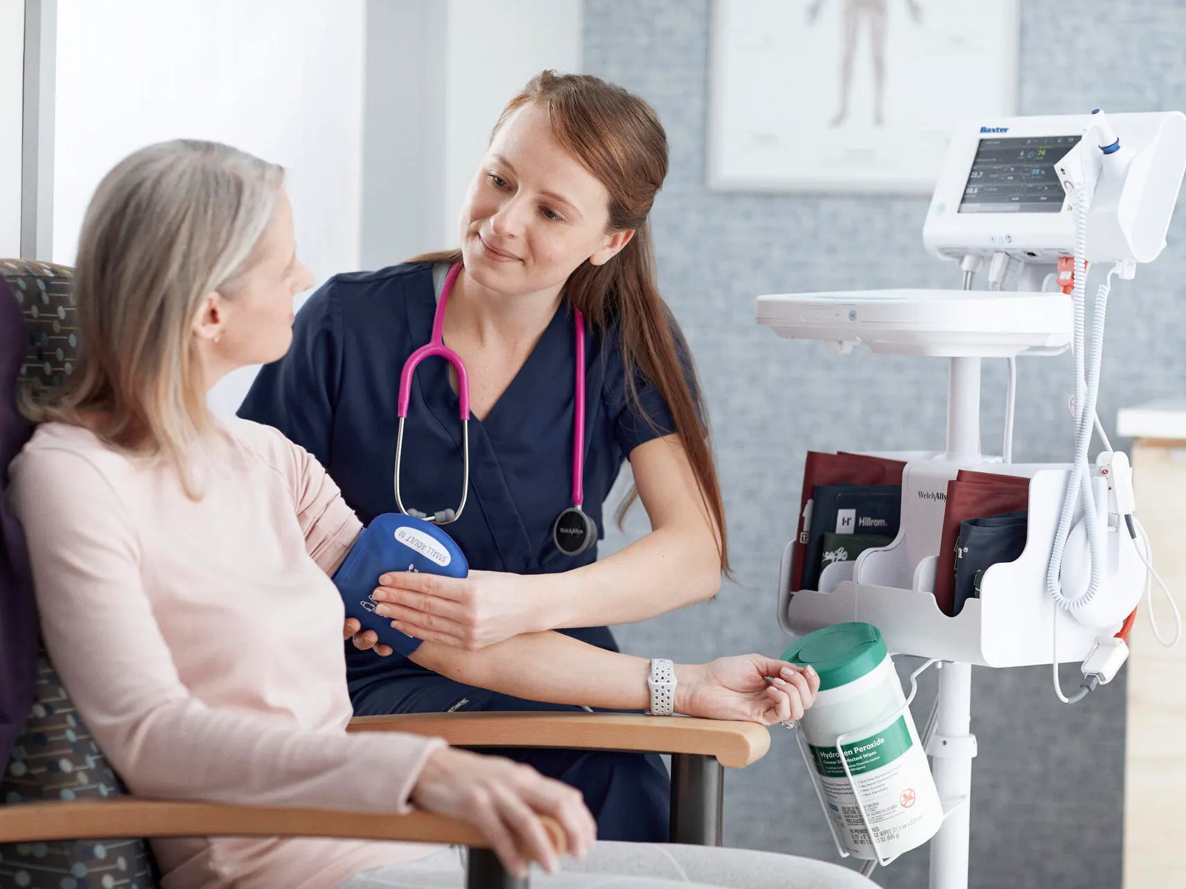 A clinician places his hand on a patient’s shoulder while talking in a primary care office.