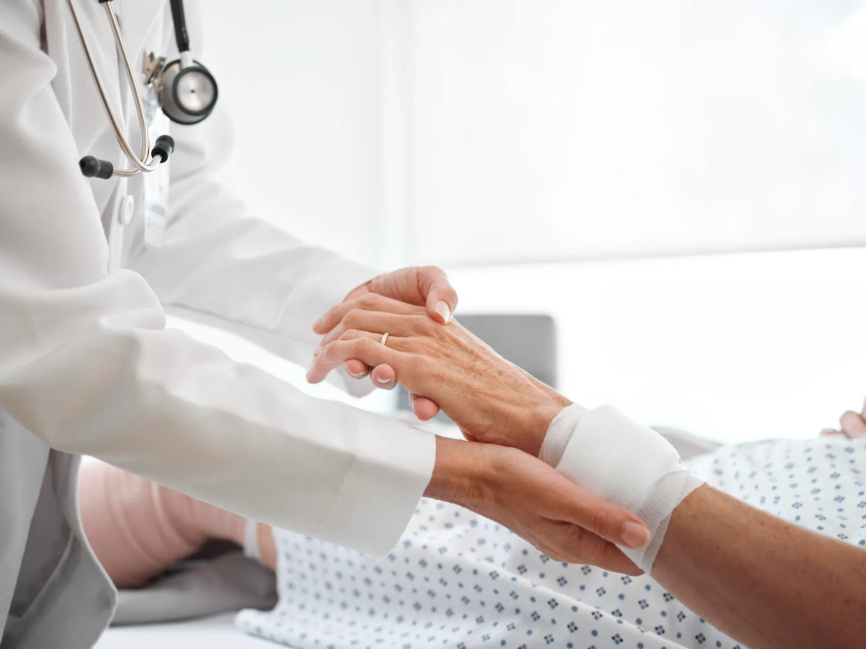 A physician supports a patient’s bandaged wrist in a hospital setting