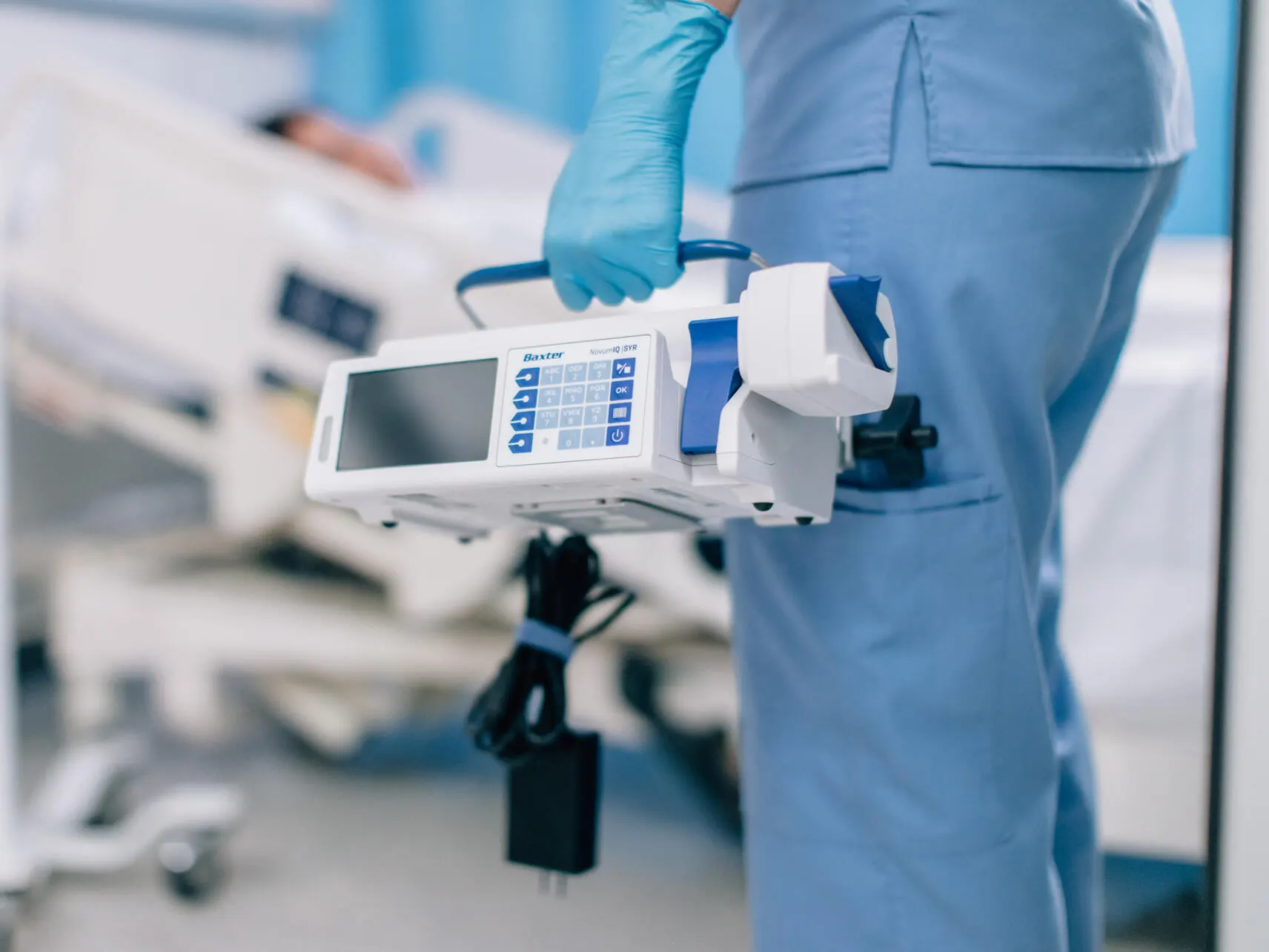 Nurse carrying infusion pump into patient room