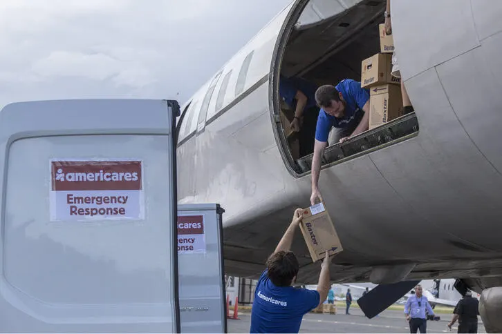 Image of volunteers unloading boxes of Baxter medical supplies from cargo plane