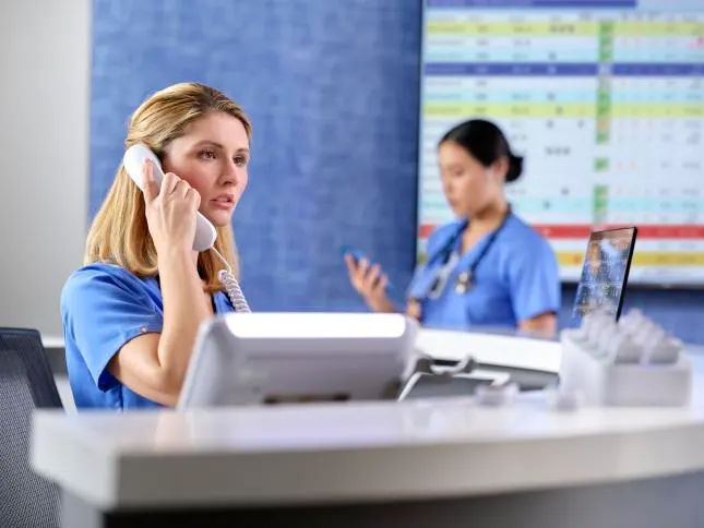 Nurse on Voalte phone at nurse station