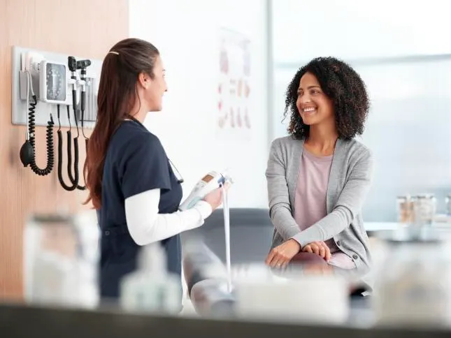A female healthcare professional and female patient share a friendly conversation