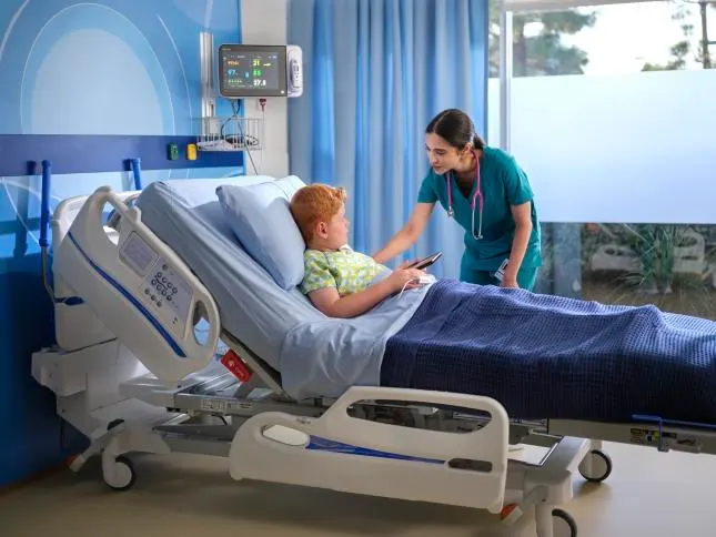 Healthcare worker checks on a pediatric patient in a hospital bed