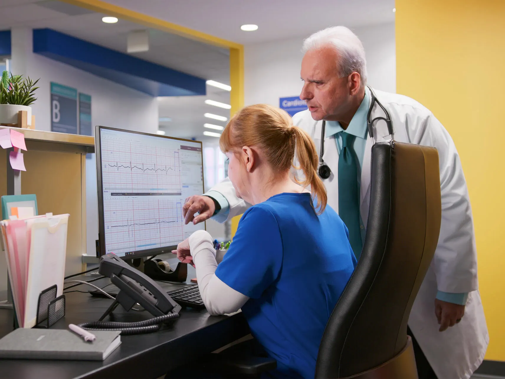 Physician and technician look at an ECG readout on a computer monitor