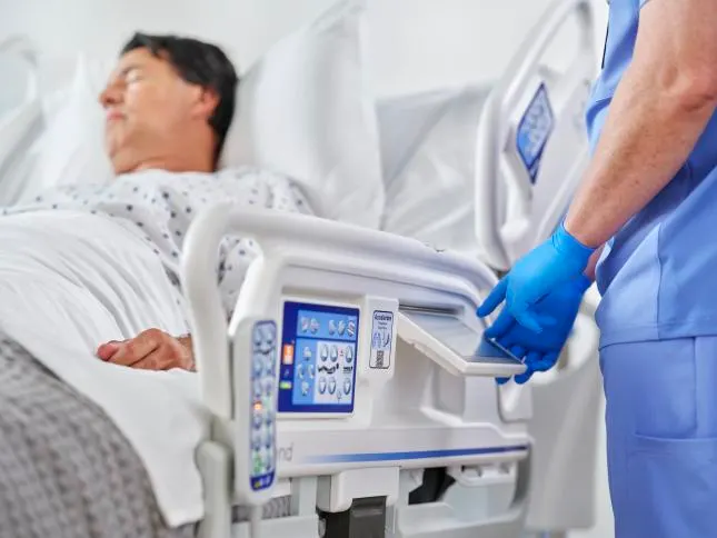 Nurse adjusting setting on a Baxter Progressa Plus ICU bed