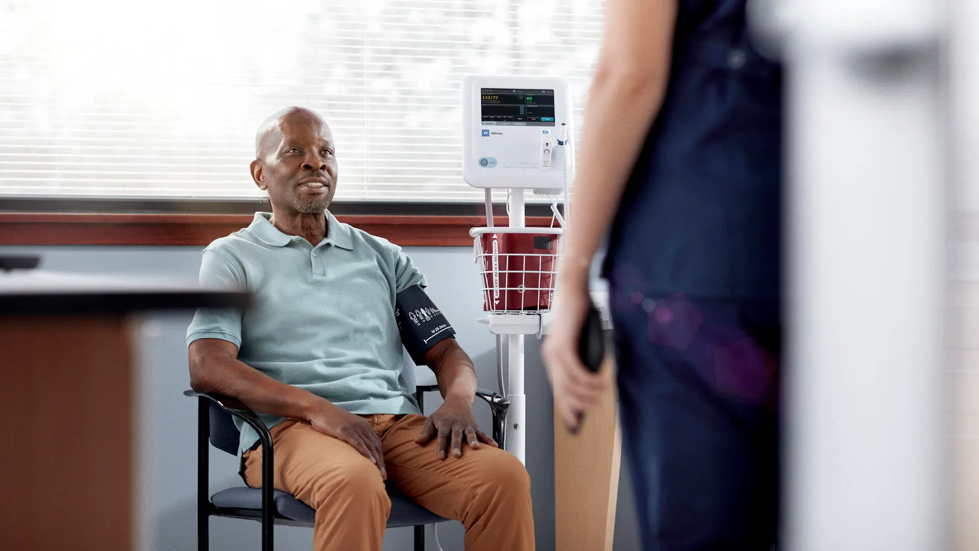 Patient siting down, waiting to get his blood pressure taken.