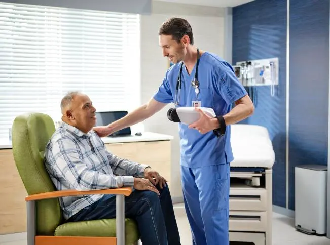 Healthcare worker talks with a patient in a doctor's office while holding the RetinaVue 700 Imager device