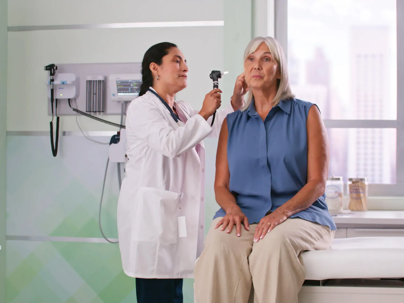 Physician using an otoscope attached to the Green Series integrated wall system to examine a patient