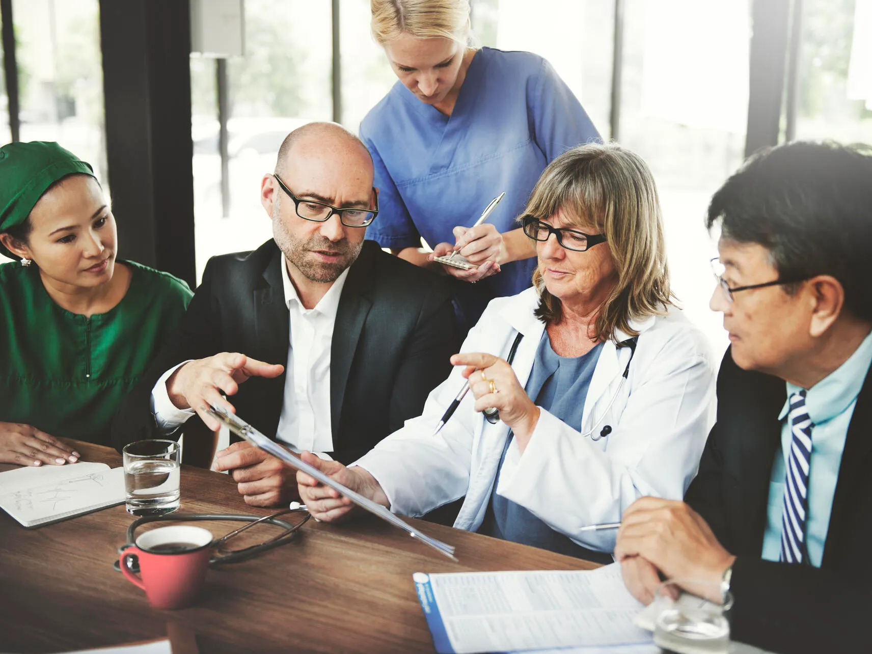 Physician discusses contents of a clipboard with a group of people.