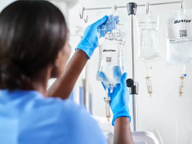 Healthcare worker hangs an IV bag on a stand