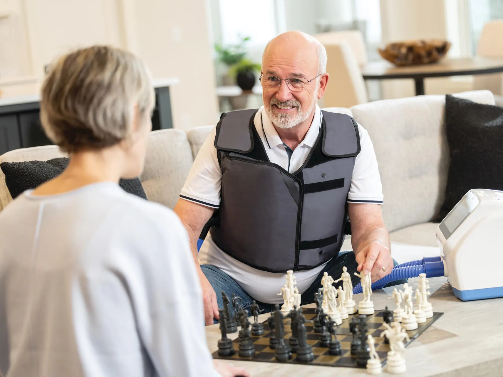 A patient playing chess while receiving respiratory therapy from The Vest APX