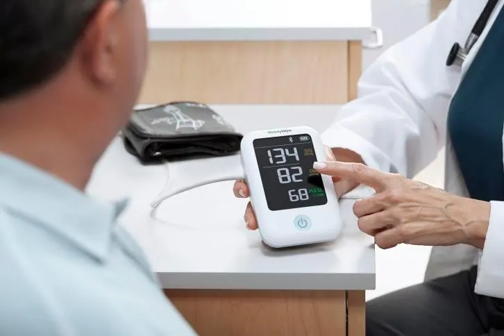 Health care profesional showing Welch Allyn Home Blood Pressure Monitor screen to patient