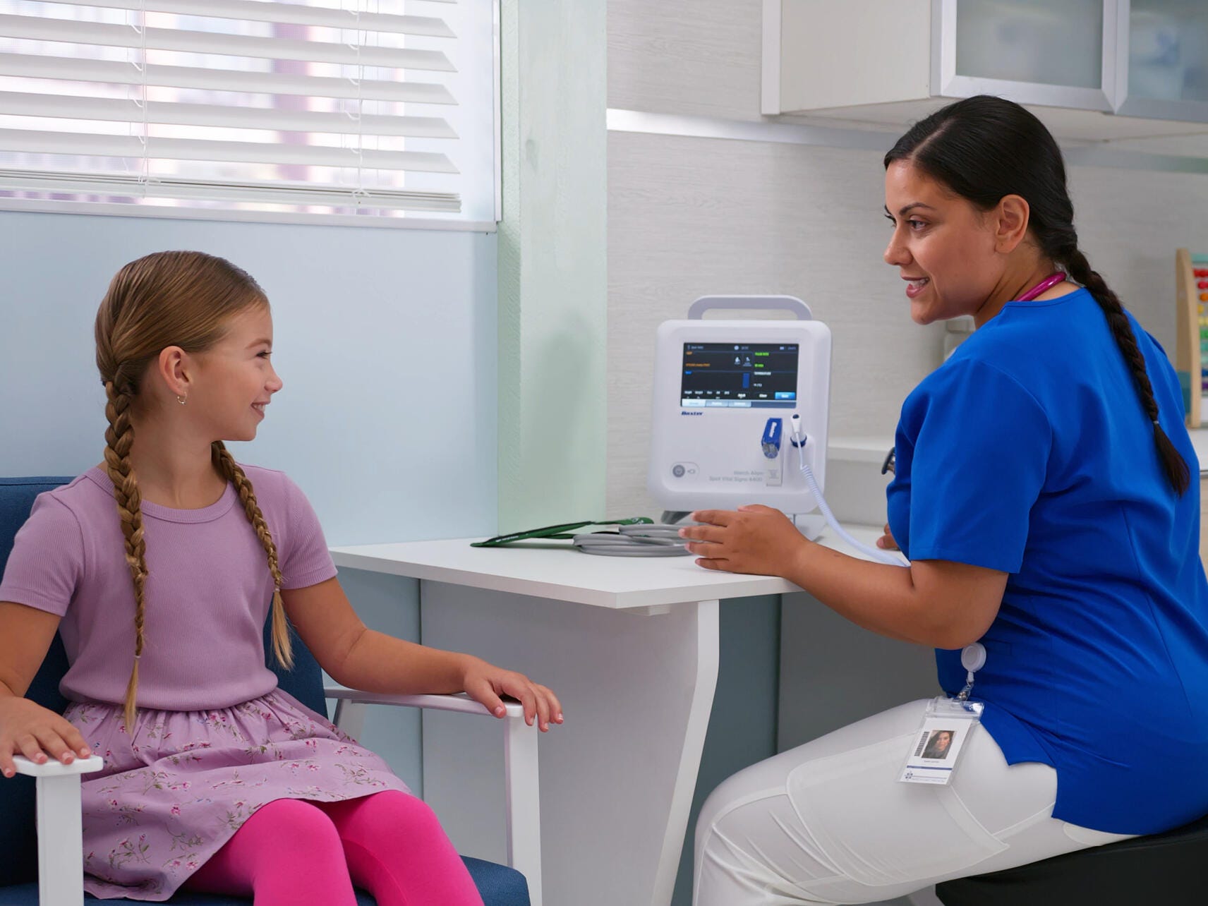 Clinician explains the Spot Vital Signs 4400 device to a pediatric patient