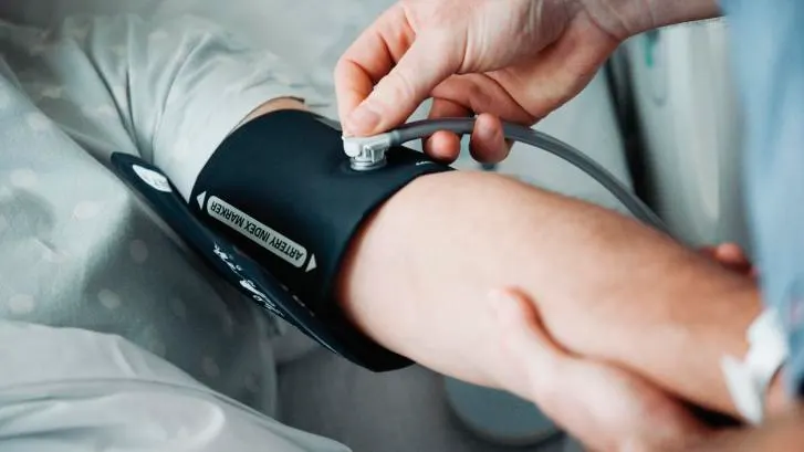Healthcare worker plugging a device into the port of a FlexiPort blood pressure cuff on a patient's arm