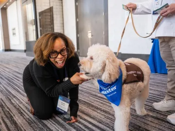 Baxter leader smiling with Pet Partners therapy dog
