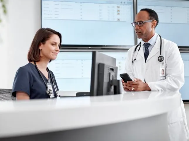 Clinician talks to a nurse at a nurse station