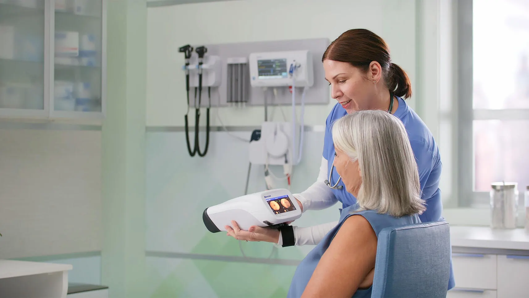 Healthcare worker shows the results of a RetinaVue 700 test to an elderly patient