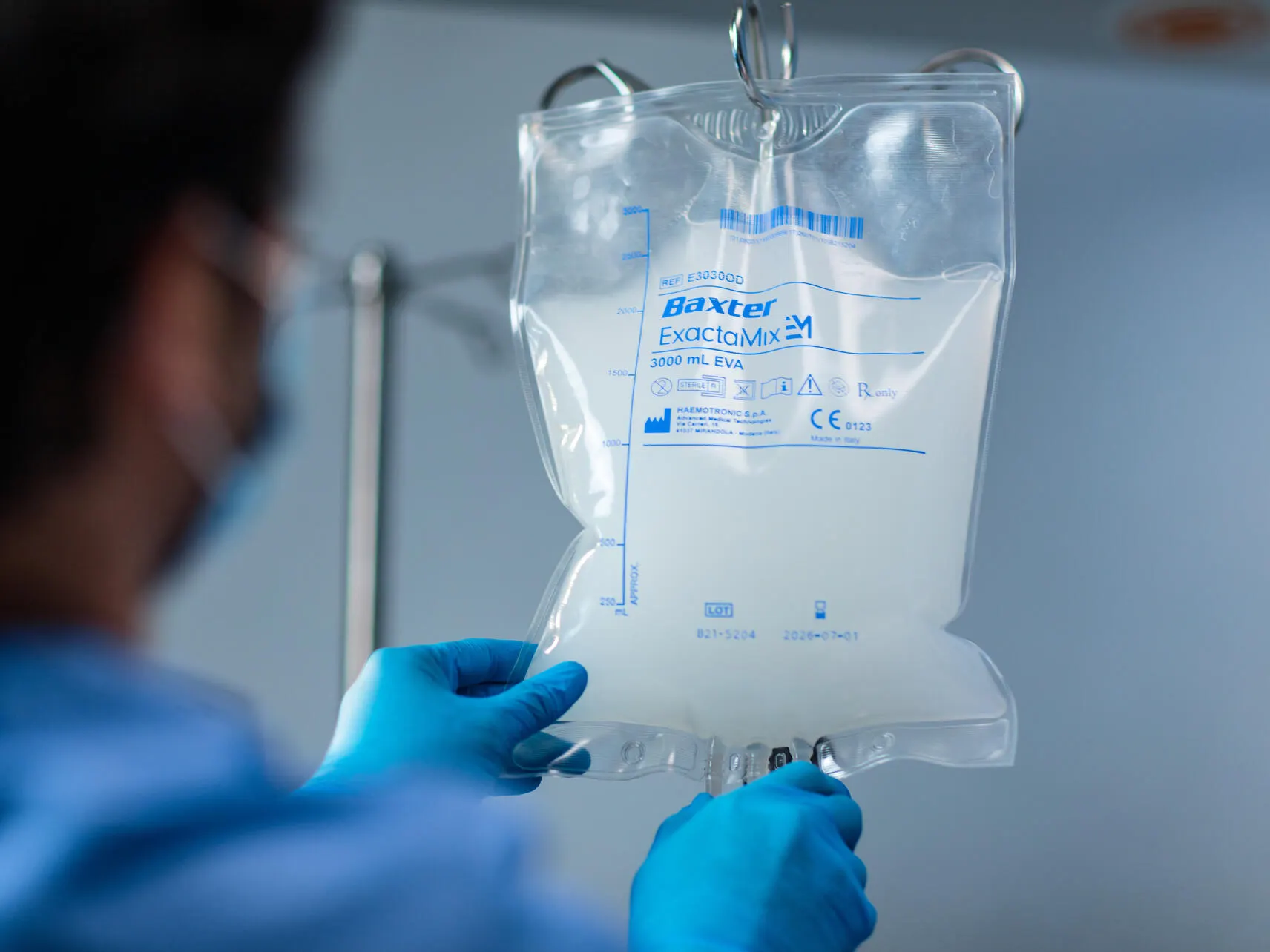 A healthcare worker positions an IV bag on an IV pole