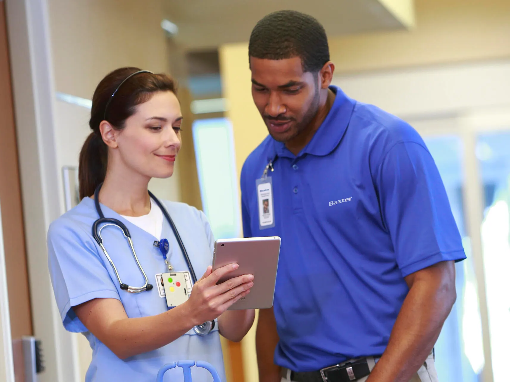 Healthcare worker shows a Baxter service rep something on a tablet device