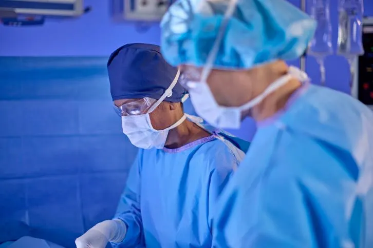 Two masked surgeons in an operating room