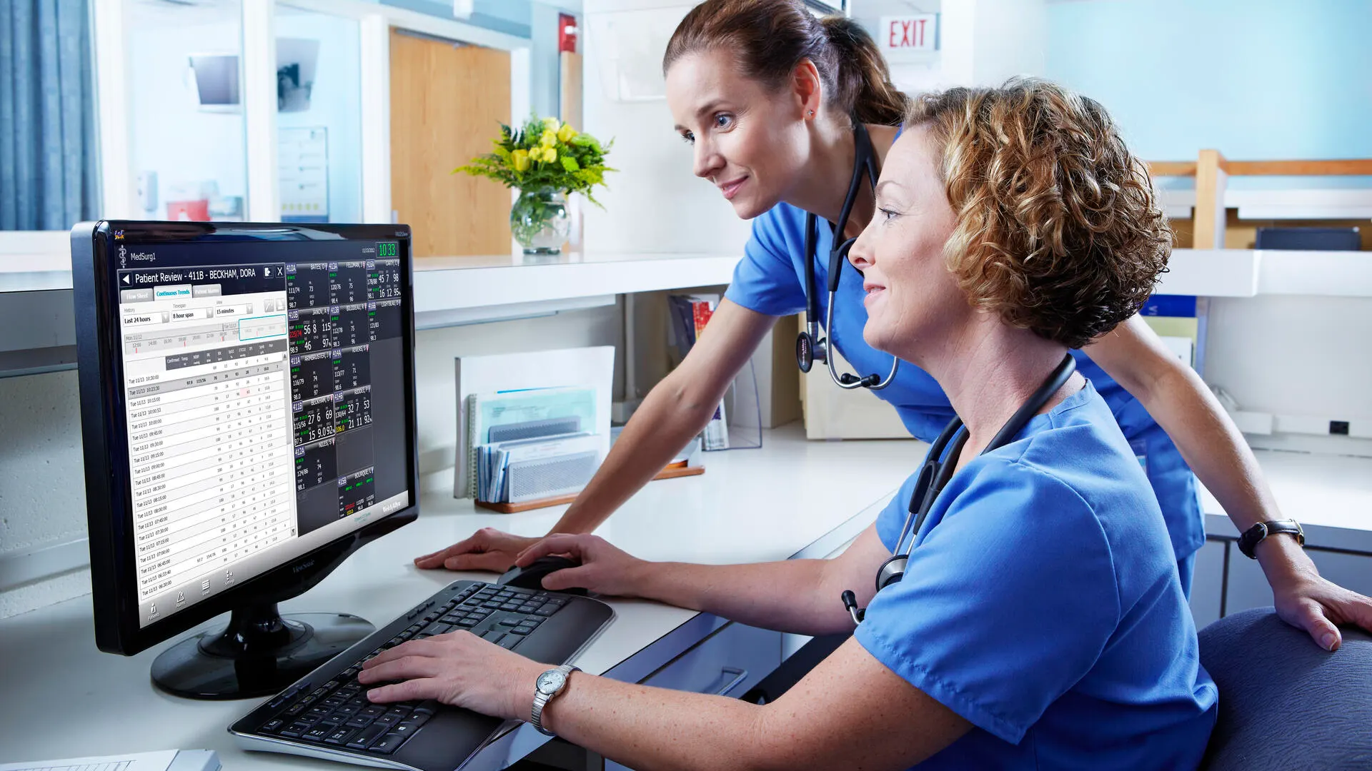 Nurses at a nursing station check on patient status
