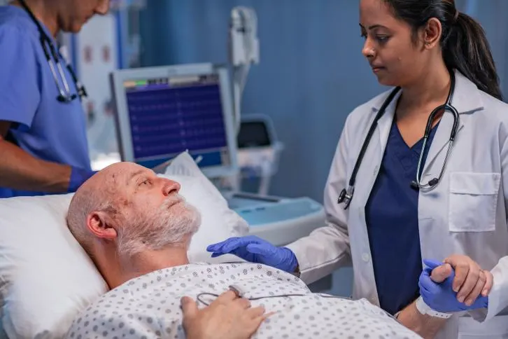 Healthcare profesional checking on patient, holding his hand