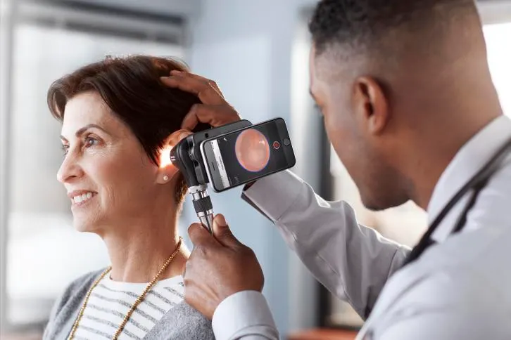 Physician uses a Welch Allyn otoscope to look into the ear of a patient