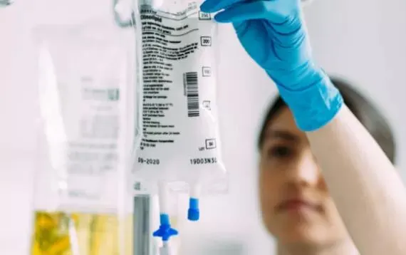 Healthcare worker hangs a bag of Clinolipid on a stand