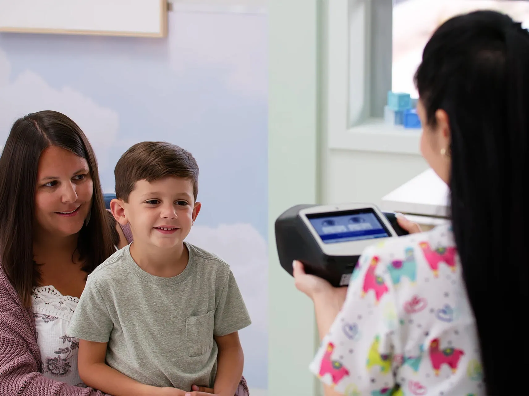 Pediatrician uses the Spot vision screener on a pediatric patient sitting on their patent's lap