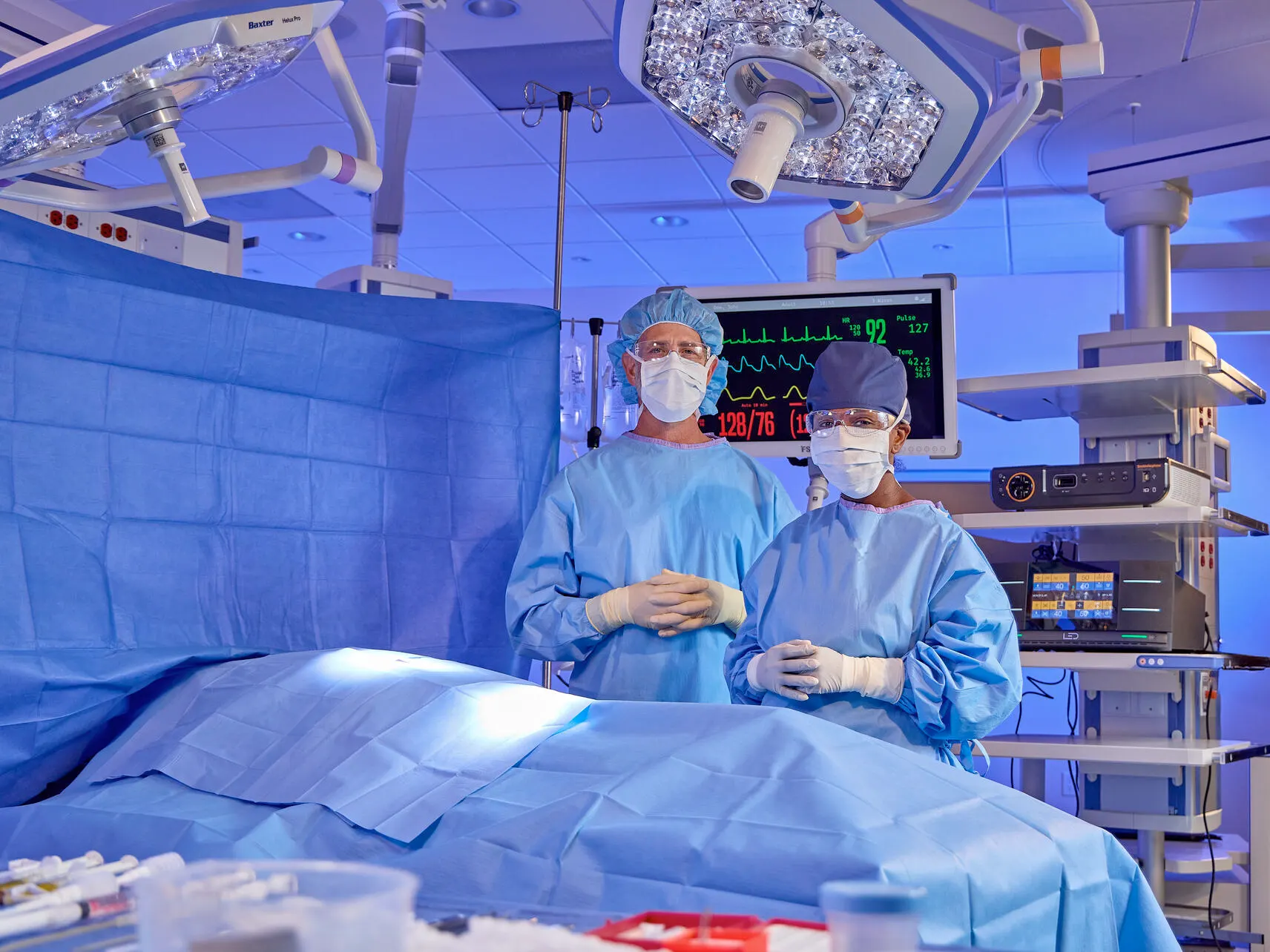 Two surgeons stand in an operating room amongst medical equipment