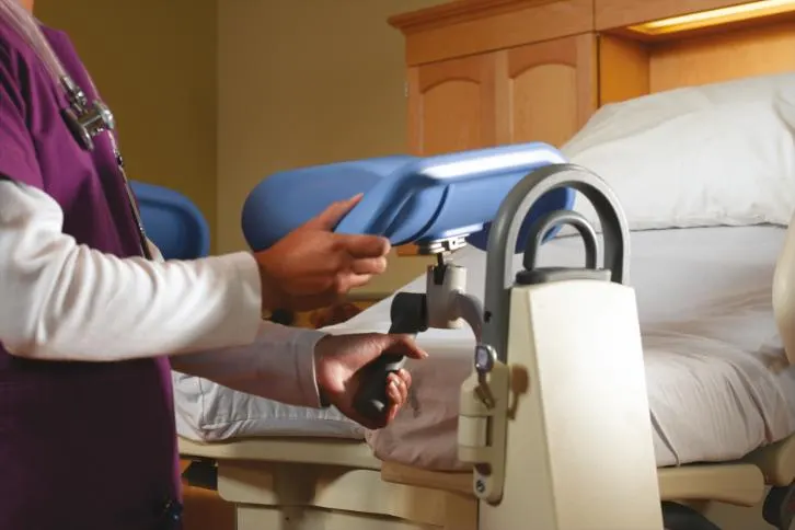 Healthcare professional adjusting stirrups on an Affinity 4 birthing bed.