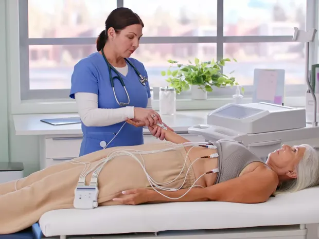 A patient lying in bed while a nurse conducts an electrocardiogram (ECG).