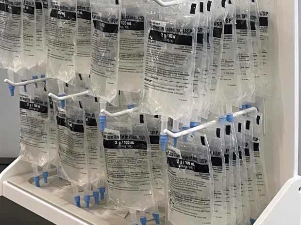 IV bags of Cefazolin Injection, USP hanging on a Baxter thawing rack