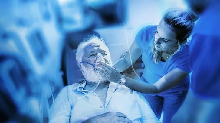 A man has a oxygen held to his face by a woman in an ambulance