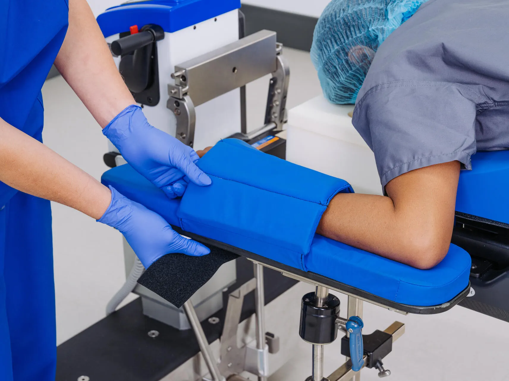 A healthcare worker adjusts a surgical patient's arm position with an accessory