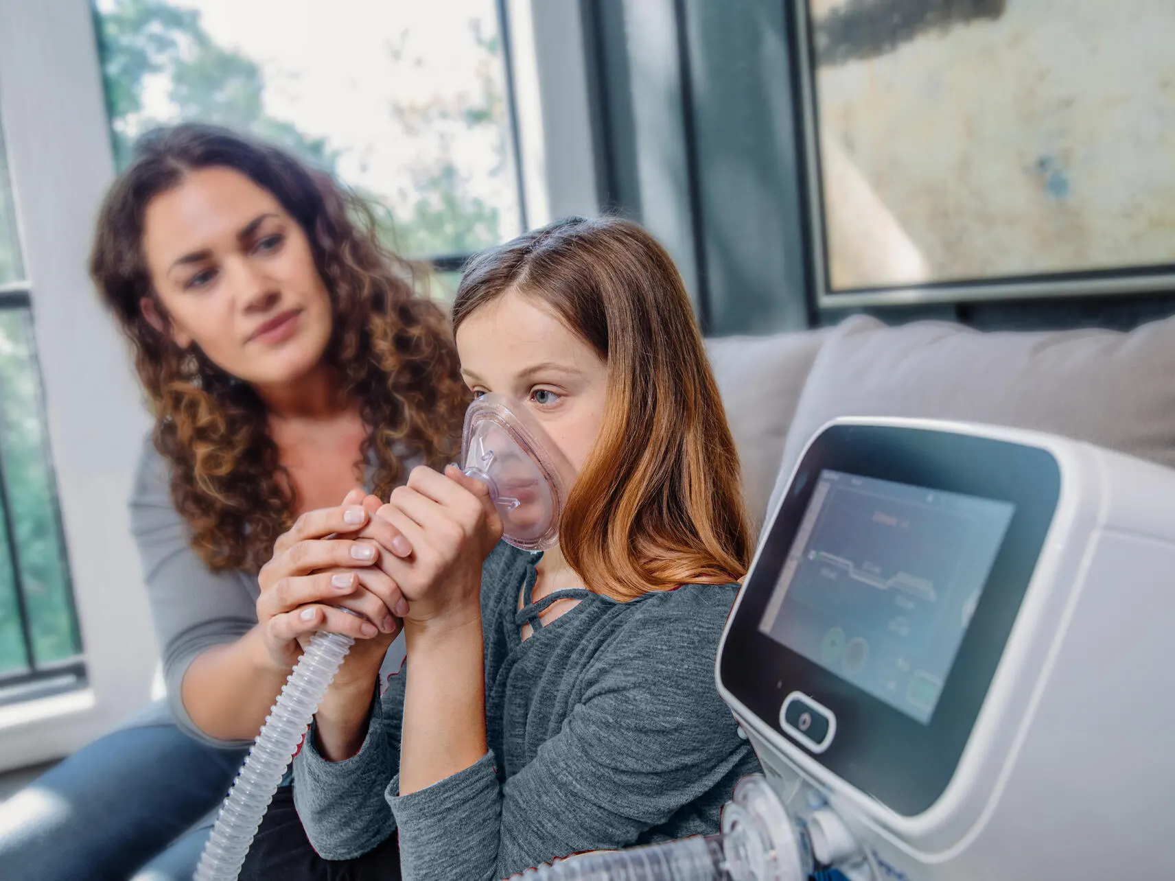 A child receiving cough therapy with the Synclara system with the assistance of an adult