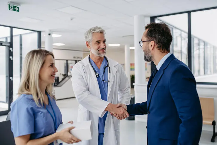 Healthcare providers shaking hands with another profesional