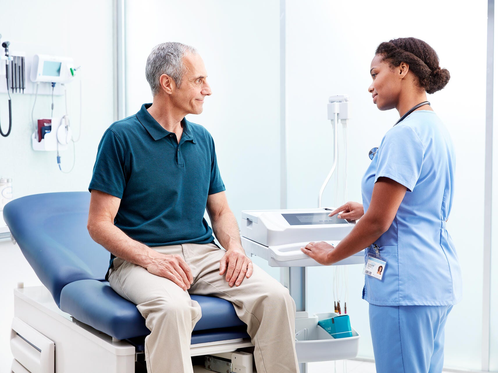 Technician talking to a patient about the results on an ELI 280 resting electrocardiograph