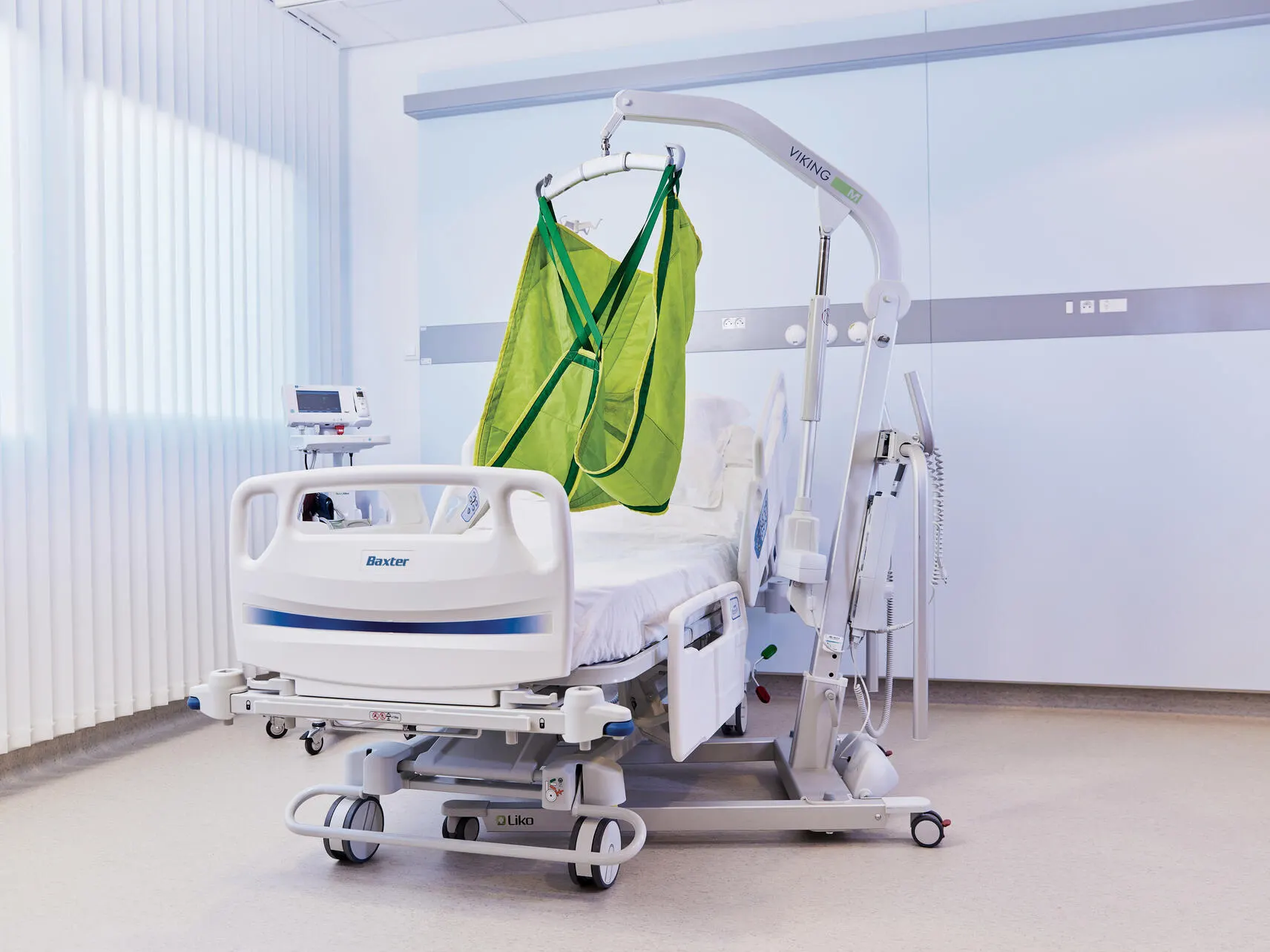 A lift assembly with sling sits in an empty patient room