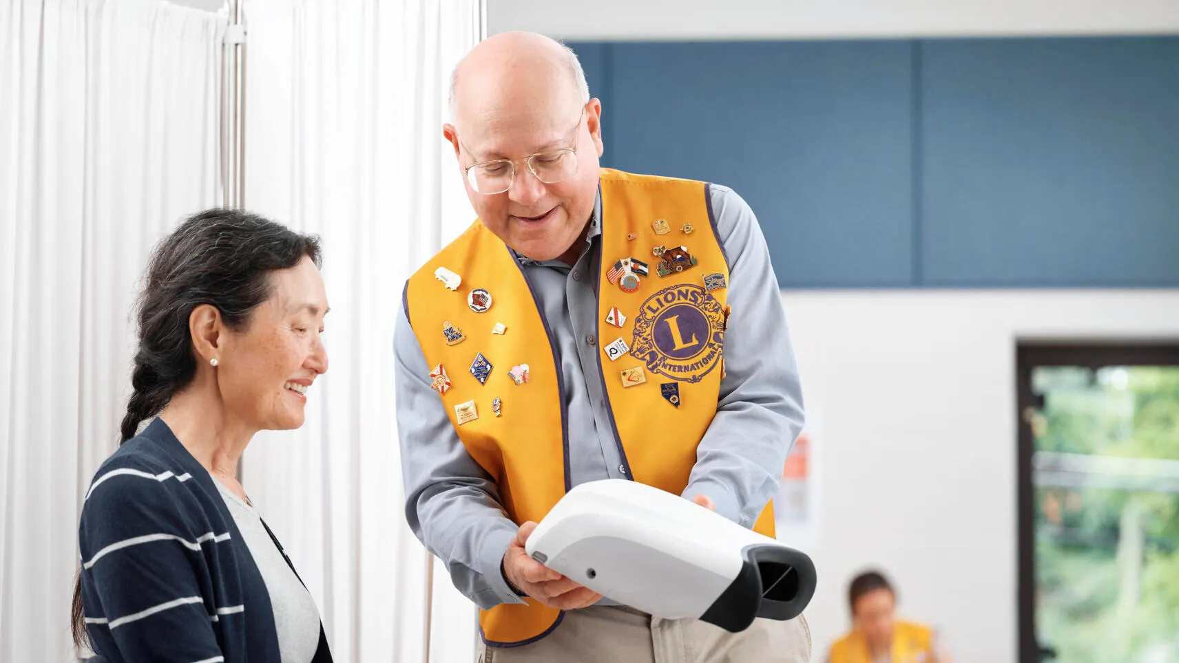 A Lions Club member shows the results of a RetinaVue assessment to a patient