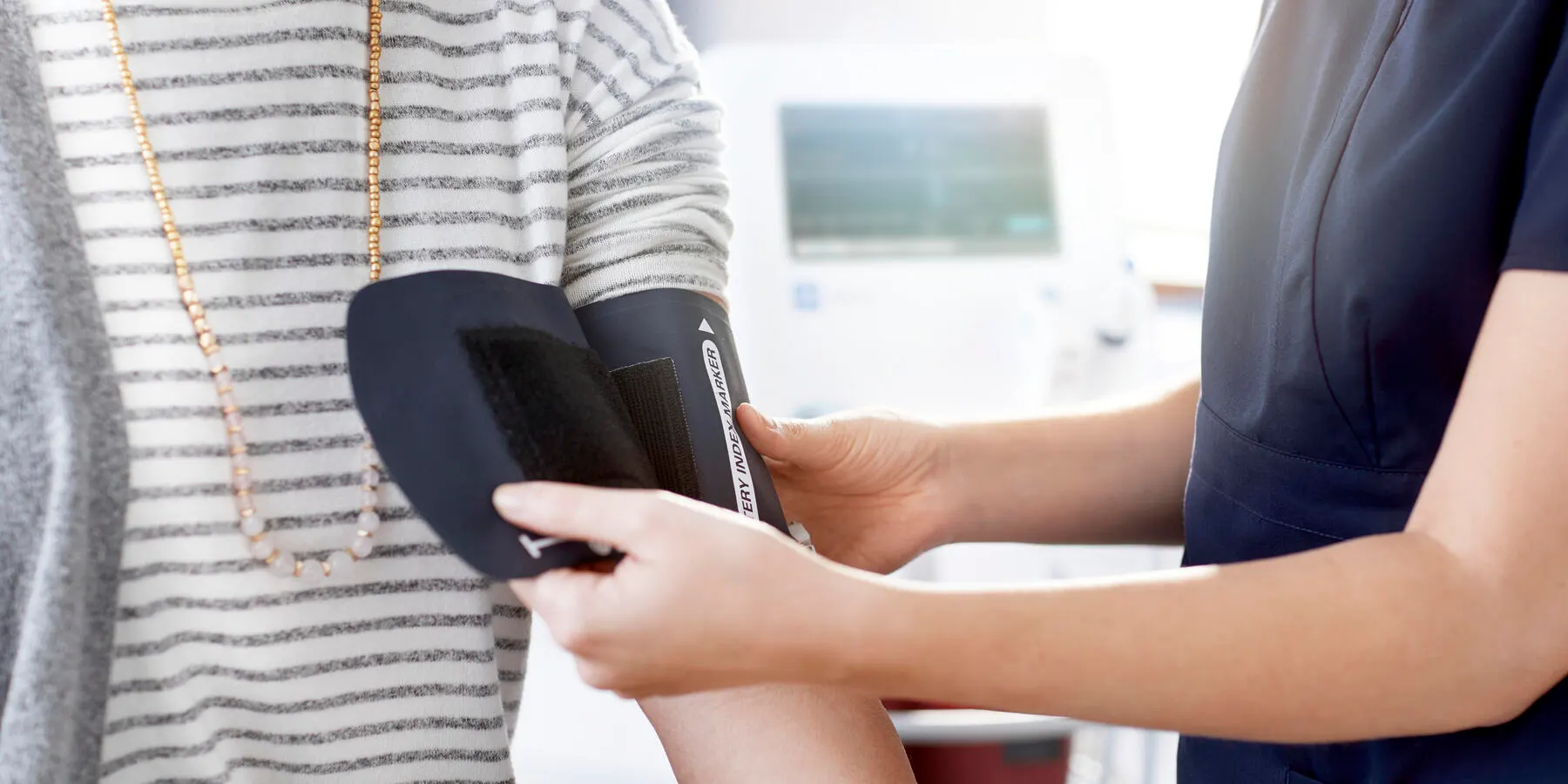 Healthcare professional wraps a blood pressure cuff around a patient's arm