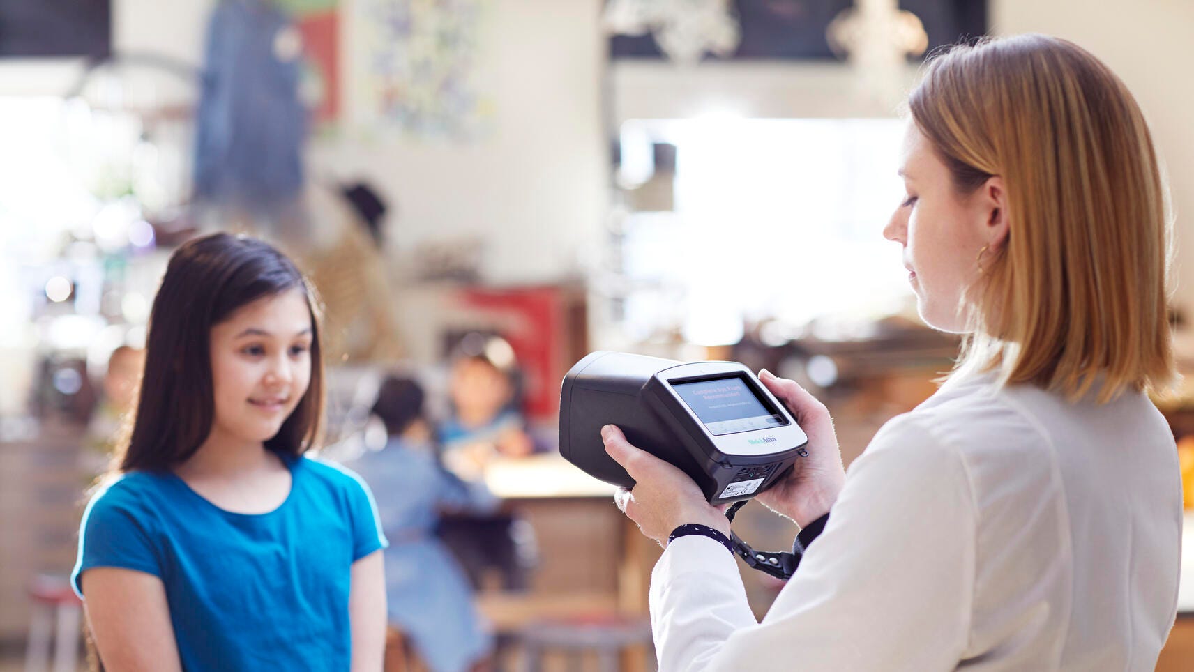 A school nurse uses the Spot vision screener on a child