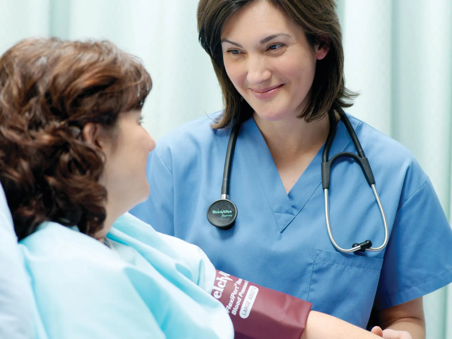 Healthcare professional smiles at a hospital patient wearing a Flexiport blood pressure cuff