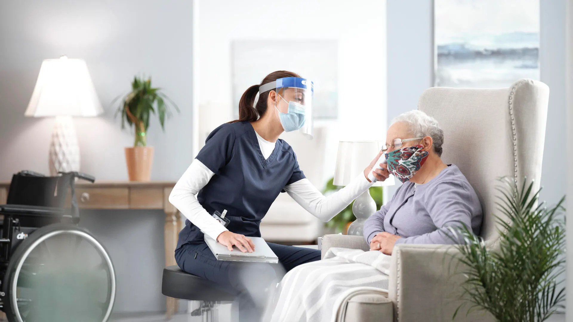 A healthcare professional cares for an elderly patient in a home setting.