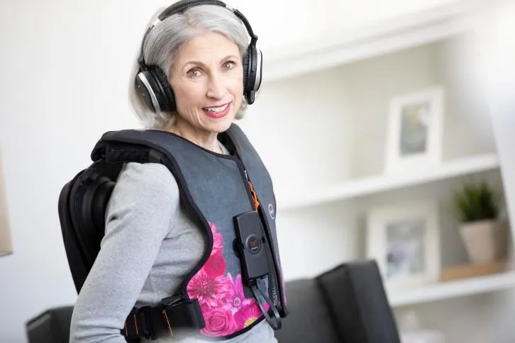 Woman sitting in living room wearing the pink MONARCH Vest