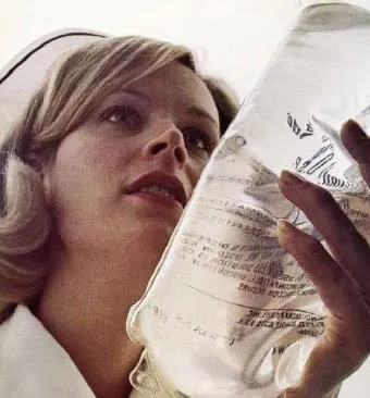 A nurse in a historical uniform holds an IV bag